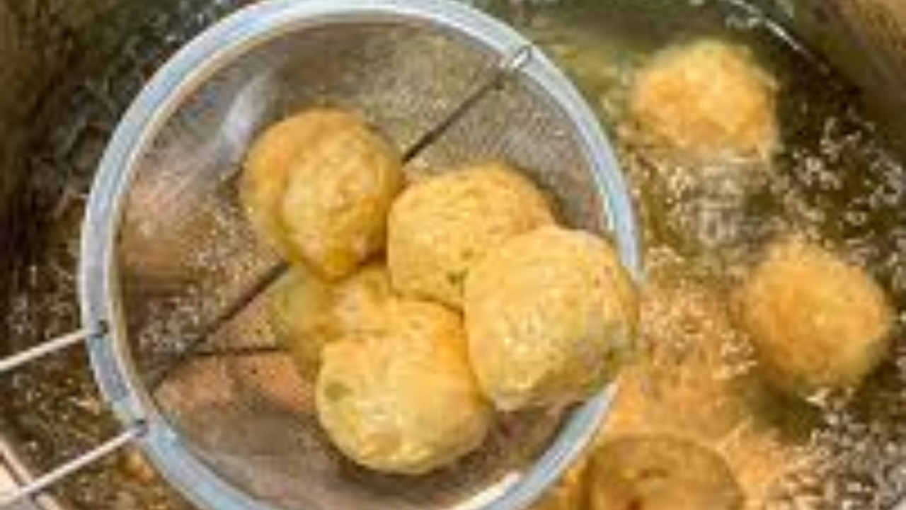 Noodle mixture being shaped into balls and frying in a pan