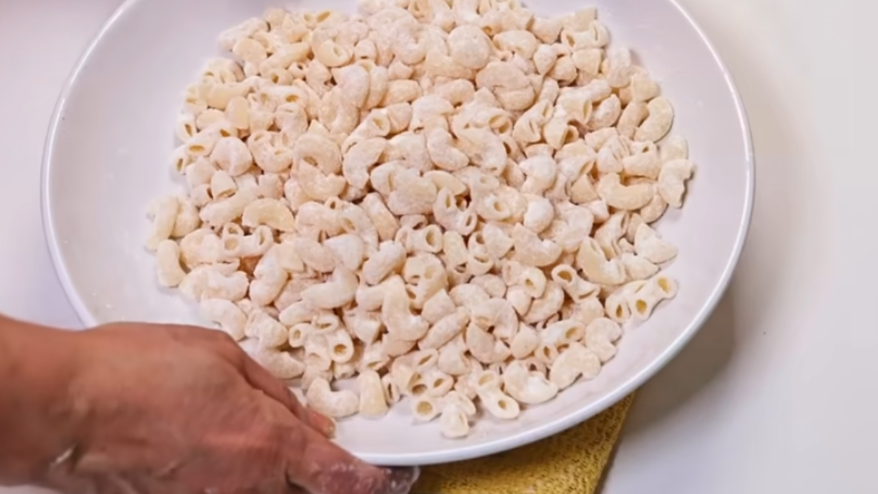 Mixing boiled macaroni with cornflour in a large bowl